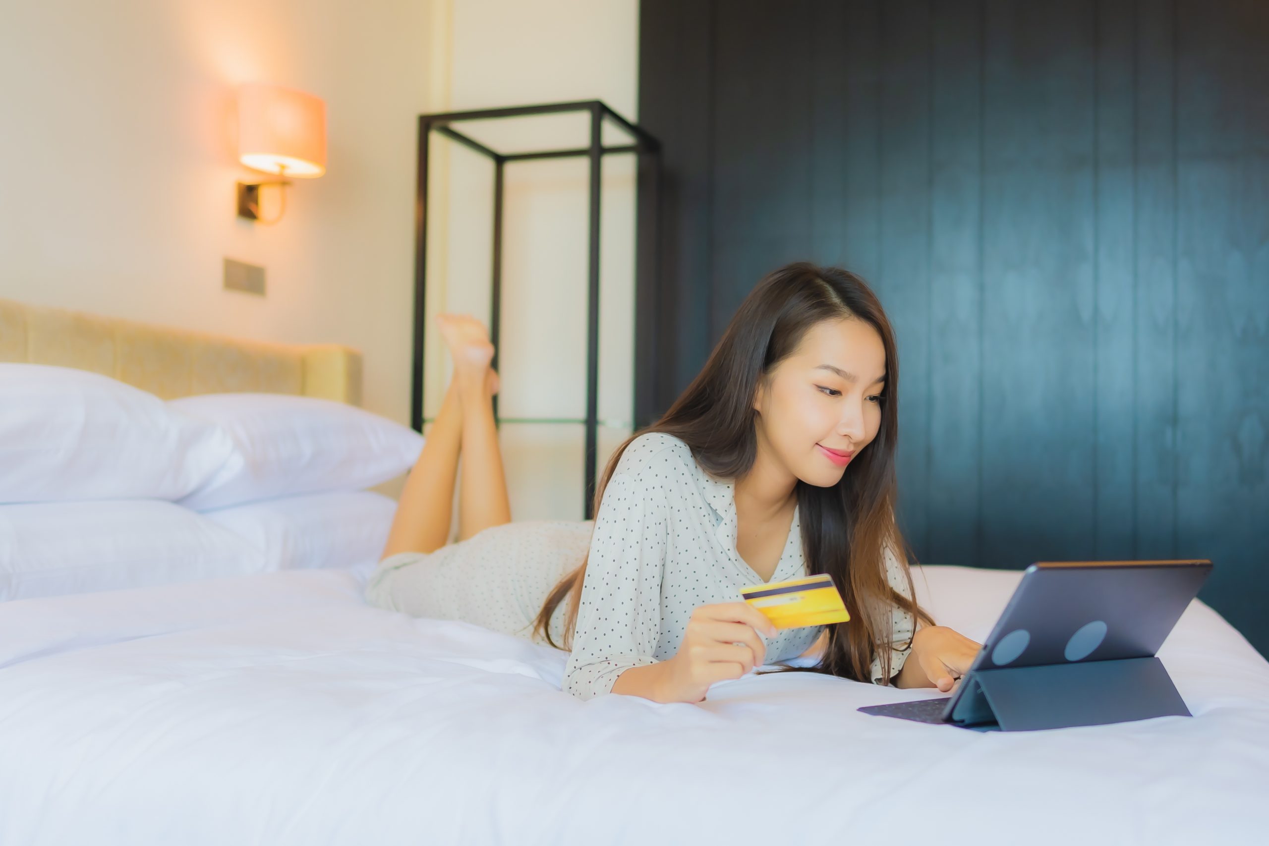 portrait beautiful young asian woman use tablet with credit card bed scaled